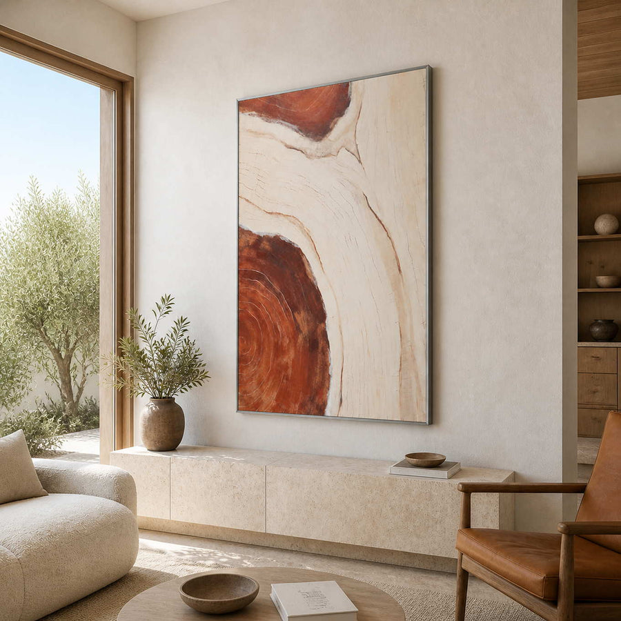 Silver framed cream and rust abstract artwork above a pale living room console.