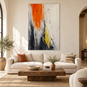 Vertical abstract artwork in orange, black, white, charcoal, and yellow, displayed in a living room without an outer frame.
