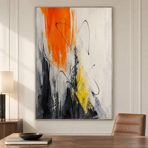 Vertical abstract artwork in orange, black, white, charcoal, and yellow, displayed in a study in a silver frame.