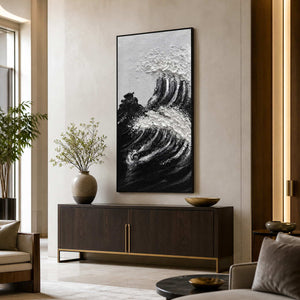 Black framed textured wave painting above a dark console in a bright hotel lobby.