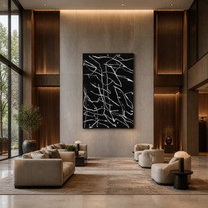 Black framed abstract line painting displayed above seating in a tall hotel lobby.