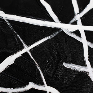 Close up of crossing white brushstrokes and visible canvas weave on black paint.