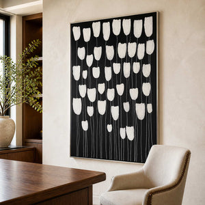 Silver framed white flower painting beside a wooden desk in a sunlit study.