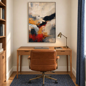 Ivory, ochre and red abstract strokes crossed by bold black bands in a silver frame, displayed in a home office.