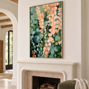 Cascading peach and blush leaves against deep green foliage in a silver frame, displayed above a fireplace.