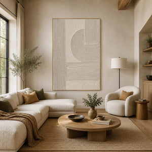 Gold framed beige relief artwork above soft living room seating and a round table.