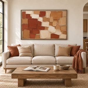 Terracotta, ochre, and cream raised block painting in a brown wood frame in a living room.