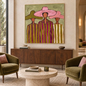 A Meeting in Style in a gold frame above a wood sideboard between olive chairs with pink cushions in a lobby.