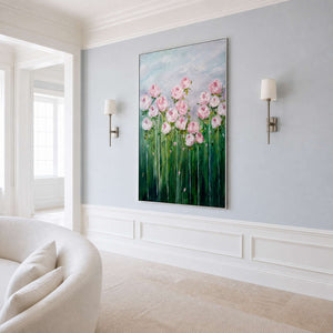 Silver framed pink flower painting between wall sconces beside curved cream living room seating.