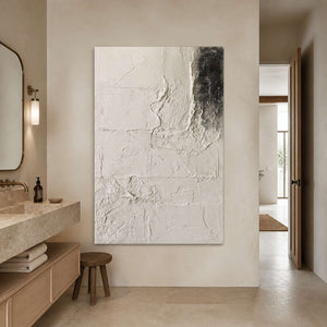 Frameless ivory abstract artwork beside a stone vanity and folded towels in a bright bathroom.