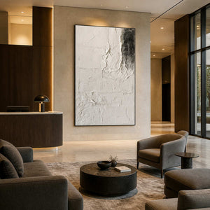Black framed pale abstract artwork beside a hotel reception counter and softly upholstered lounge seating.