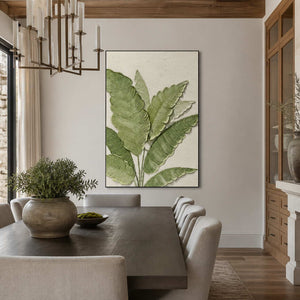 Black-framed botanical wall art beside a wooden dining table and cream upholstered chairs.