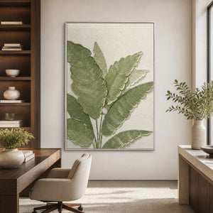 Silver-framed botanical wall art beside a wooden desk in a bright home office.