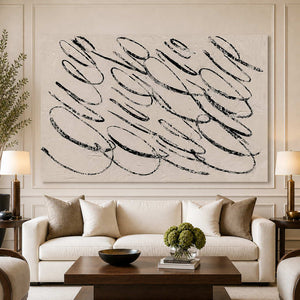 Frameless black looping abstract wall art above a cream living room sofa.