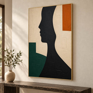 Hand-painted black profile canvas with ivory, green, and orange forms, displayed in an entryway in a gold frame.