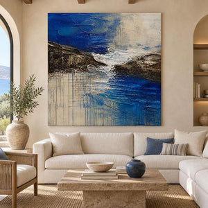 Square cobalt sea, dark rock, and ivory surf textured painting, displayed in a living room without an outer frame.