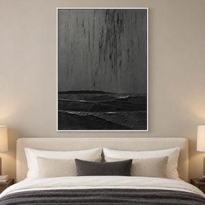Charcoal rain marks descending over sculpted black terrain in a vertical composition, displayed in a bedroom in a white frame.