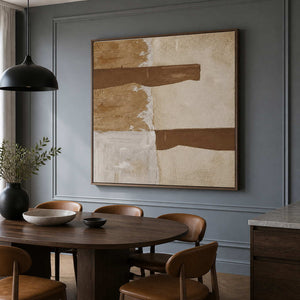 Wood framed cream and brown abstract painting beside a round dining table.