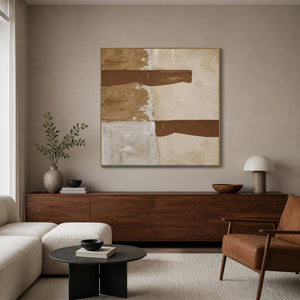 Gold framed abstract painting with two brown strokes above a living room console.