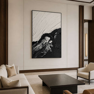 Black and white textured painting beside cream seating and a dark hotel coffee table.