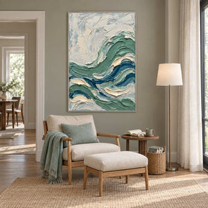 A Sea Breeze in a silver frame above a cream armchair with a green cushion in a quiet reading corner.