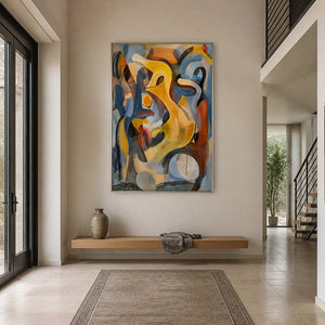 Silver framed yellow and blue abstract painting above a bench in a tall entryway.
