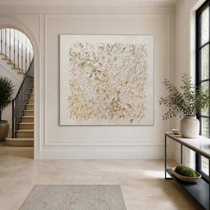 Silver-framed white textured artwork beside an entryway staircase and a slim black console.