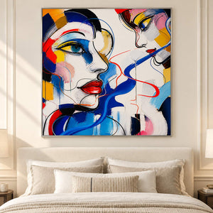 Hand-painted square portrait canvas with expressive faces and vivid color, displayed in a bedroom in a silver frame.