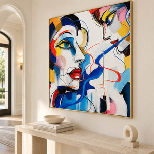 Hand-painted square portrait canvas with expressive faces and vivid color, displayed in an entryway in a gold frame.