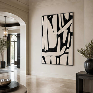 Black framed cream and black abstract artwork beside an archway in a furnished hotel lobby.