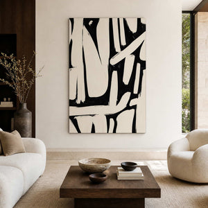 Frameless cream and black abstract artwork above a wooden table between cream living room seating.