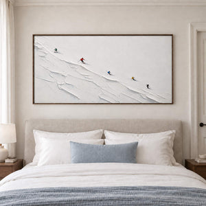 Tiny colorful skiers crossing a ridged white slope in a brown wood frame, displayed above a bed.