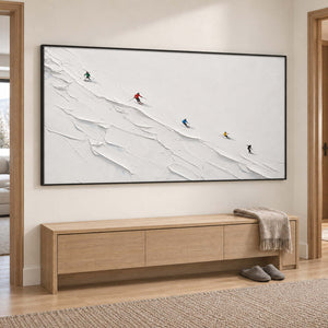 Tiny colorful skiers crossing a ridged white slope in a black frame, displayed in a hallway.