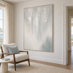 Soft gray and ivory vertical textures fading into pale blue in a silver frame, displayed beside seating in a lounge.