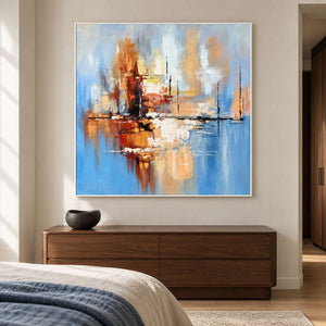 In a bedroom above a wooden dresser, a white-framed abstract painting pairs pale blue with amber, cream and fine black lines.