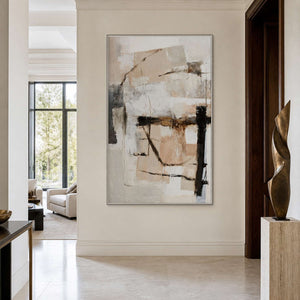 Silver framed neutral abstract artwork beside a bronze sculpture in a light residential entryway.
