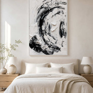 White framed monochrome painting above a cream bed with matching lamps and pale bedding.