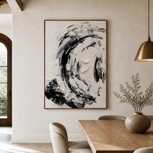 Wood framed black and white abstract painting beside a dining table beneath exposed ceiling beams.