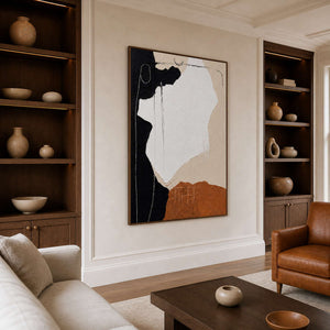 Wood-framed abstract wall art between illuminated shelves in a comfortable library lounge.
