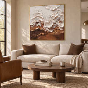 At Ease in a gold frame above a cream sofa with brown cushions and a round wood coffee table.