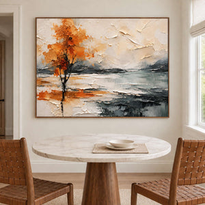 An orange autumn tree reflected beside a gray lake in a brown wood frame, displayed above a dining table.
