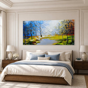 White framed colorful woodland landscape with a blue channel above a pale upholstered bed.