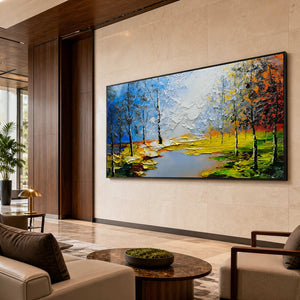 Black framed panoramic woodland painting with bright autumn banks above seating in a hotel lobby.