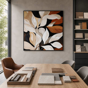 Black framed cream and rust leaf artwork beside material samples in an architectural studio.