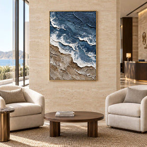 Beyond the Shore in a gold frame above two cream armchairs and a round wood table in a commercial lobby.