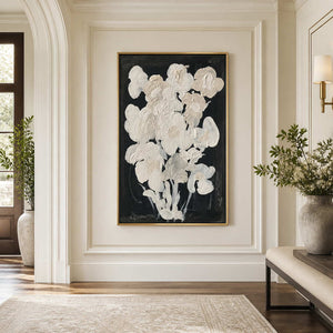 Gold framed cream floral artwork on a bright hallway wall near an arched doorway.
