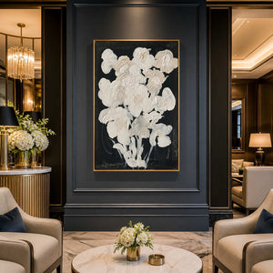Gold framed cream floral artwork on a dark hotel lobby wall between lounge chairs.