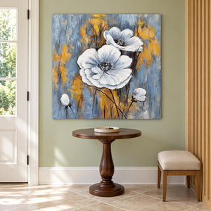 In an entryway above a console or bench, an artwork with no outer frame shows two large white flowers and small buds on a blue-gray ground with ochre marks.