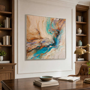 Silver framed turquoise abstract artwork above a wooden desk between tall bookshelves.