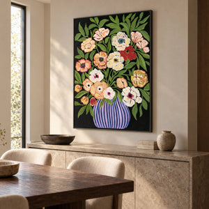 Artwork showing cream, peach and red flowers with green leaves in a purple-blue striped vase on black above a dining-room sideboard, with a black frame.
